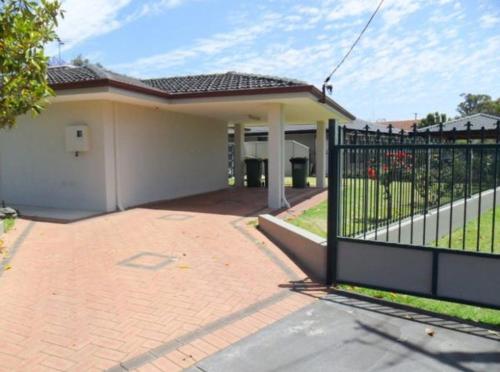 a house with a black gate and a driveway at Cozy room near CBD airport in Perth