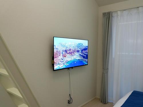 a flat screen tv on a wall in a bedroom at OUCHI HOTEL Onaganishi in Hiroshima