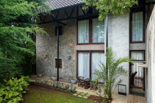 a stone house with a patio and a garden at Tathya Hills - Luxe Garden Retreat In The Hills in Nuwara Eliya