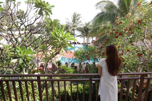 a woman in a white dress standing on a balcony looking at a pool at Villa Aria Boutique Muine in Mui Ne