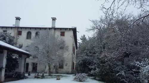 an old house with snow on the ground in front of it at Villa Mainardi Agriturismo in Camino al Tagliamento