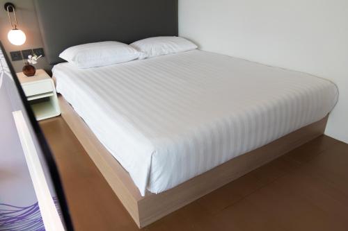 a bedroom with a large bed with white sheets at Studio M Hotel in Singapore