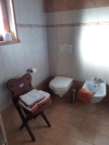 Un baño con inodoro, lavabo y silla. en L'Etoile Du Berger, en Lillianes