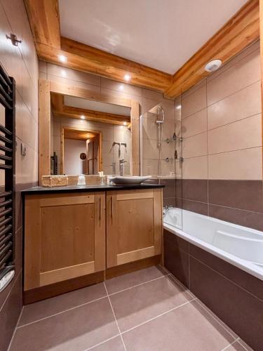 une salle de bain avec une baignoire et un lavabo et une baignoire dans l'établissement Chalets d'Angèle D5 - Multipass inclu, à Châtel