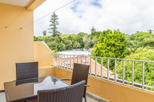 a balcony with a table and chairs and trees at Apartamento Mãe de Deus in Ponta Delgada