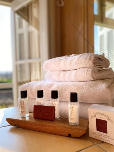 a pile of towels on a table with three bottles of soap at Château Maucaillou in Moulis-en-Médoc