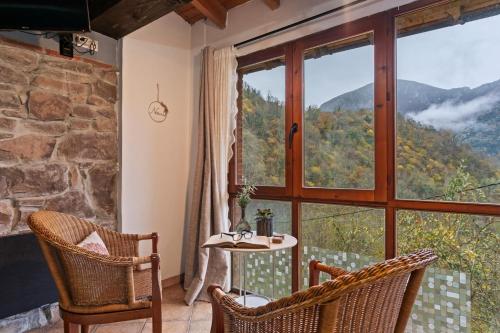a room with a table and chairs and a large window at Carbayu Senda del Oso in Proaza