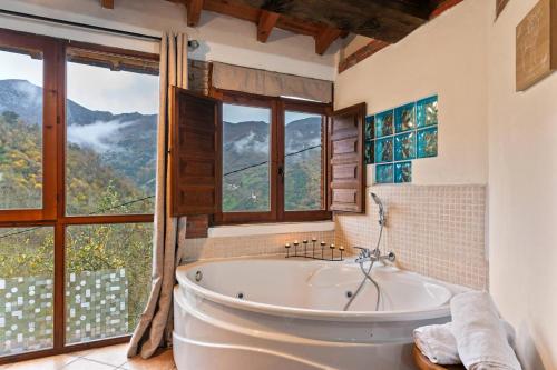 a bathroom with a tub and a large window at Carbayu Senda del Oso in Proaza