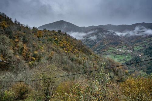 a view of a mountain with clouds in the valley at Carbayu Senda del Oso in Proaza