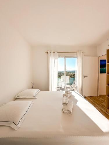 un grand lit blanc dans une chambre avec une fenêtre dans l'établissement Casa Luna Di Santa Lucia, à Sainte-Lucie de Porto-Vecchio