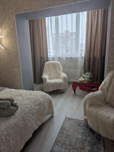 a bedroom with a bed and a chair and a window at Центр Либідь Плаза Новобудова провулок Лапушкіна 9 in Khmelnytskyi