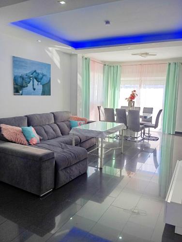 a living room with a couch and a table at Chalet con jardin privado y piscina para disfrutar con la familia y amigos in Punta Umbría