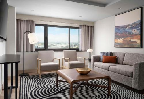 a living room with a couch and chairs and a table at Sonesta Los Angeles Airport LAX in Los Angeles