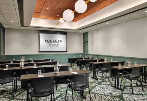 a conference room with tables and chairs and a screen at Sonesta Los Angeles Airport LAX in Los Angeles