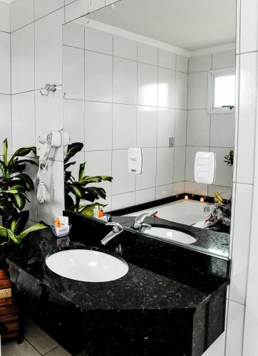 a bathroom with a sink and a large mirror at Vivendas Hotel in Erechim