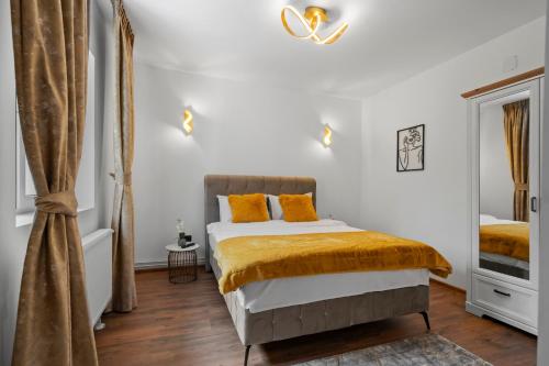 a bedroom with white walls and a bed with orange pillows at SEVEN Apartments in Predeal