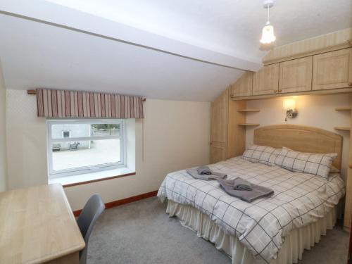 a bedroom with a bed and a window and a table at Cwellyn in Pwllheli