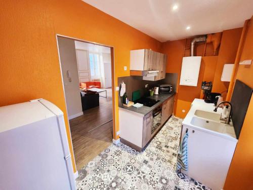 - une cuisine avec des murs orange, un évier et un réfrigérateur dans l'établissement Appartement de Louise et Adrien, à Gray
