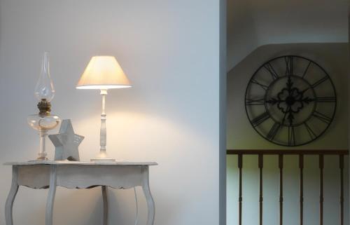 a table with a lamp and a clock on the wall at Le Relais De La Motte in Soignies
