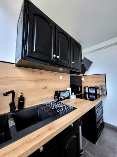 - une cuisine avec des placards noirs et un évier dans l'établissement Bel appartement Lagny sur Marne, à Lagny-sur-Marne