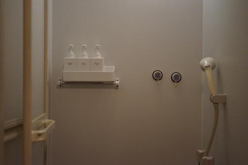 a bathroom with three bottles on a wall at Guest House FUTARENO in Yokohama