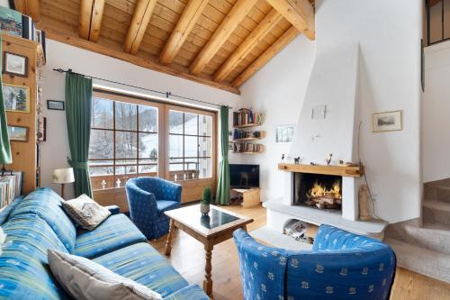 Una sala de estar con un sofá azul y una chimenea. en Chalet St Moritz, en Madulain