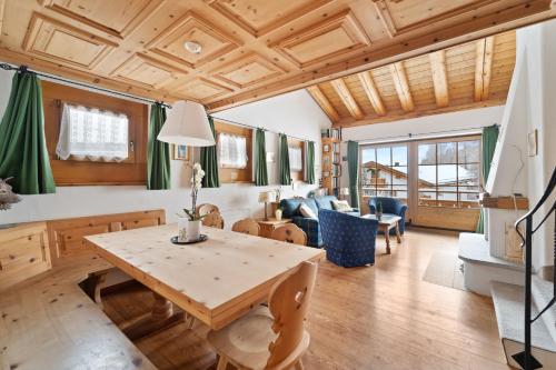 Una sala de estar con techo de madera y una mesa. en Chalet St Moritz, en Madulain
