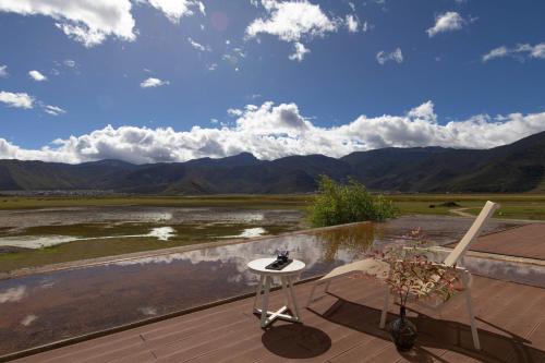 a patio with two chairs and a table and a view of the mountains at 丽思漫 心宿穹庐四野供氧庄园 in Shangri-La
