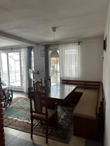 a dining room with a wooden table and a couch at Vila Jovana i Andrea in Mavrovo