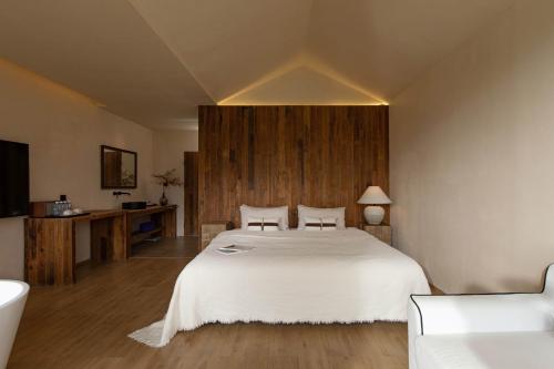 a bedroom with a white bed and a wooden wall at 丽思漫 心宿穹庐四野供氧庄园 in Shangri-La