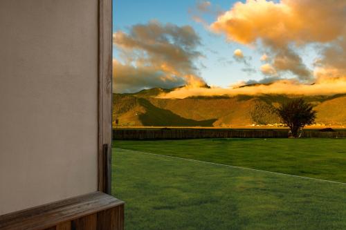 a window view of a field of grass with a sunset at 丽思漫 心宿穹庐四野供氧庄园 in Shangri-La