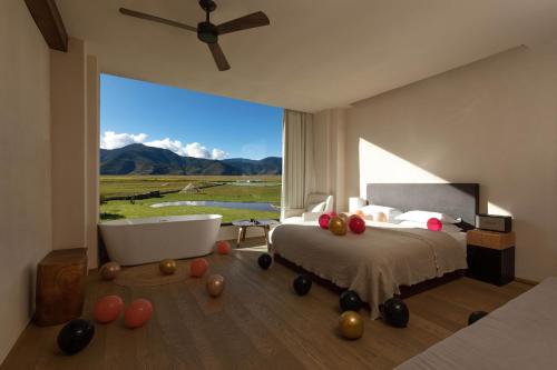 a bedroom with a tub and a bed with a large window at 丽思漫 心宿穹庐四野供氧庄园 in Shangri-La