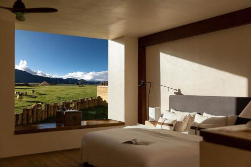 a bedroom with a bed and a large window with a view at 丽思漫 心宿穹庐四野供氧庄园 in Shangri-La