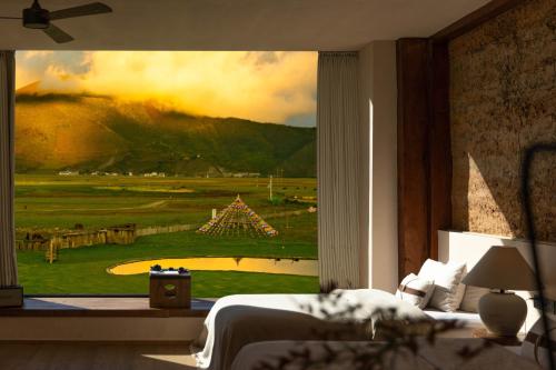 a bedroom with a view of a golf course through a window at 丽思漫 心宿穹庐四野供氧庄园 in Shangri-La
