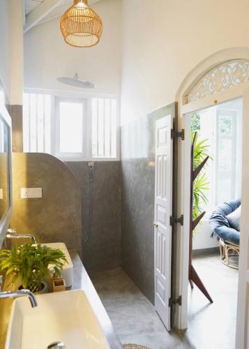 a bathroom with a sink and a window and a door at Shaka Villa in Dickwella