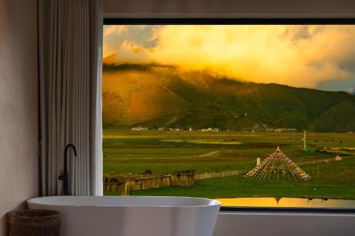 a large window with a view of a field at 丽思漫 心宿穹庐四野供氧庄园 in Shangri-La