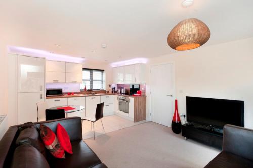 a living room with a couch and a kitchen at DBS Serviced Apartments - The Coach House in Castle Donington