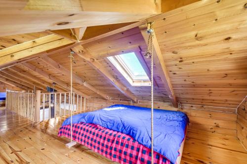 una cama en una cabaña de troncos con ventana en Bellevue Log Cabin with Gas Grill and Creek Access, en Bellevue