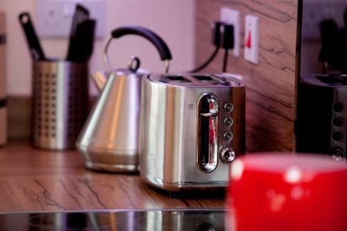 a kitchen counter with two silver tea pots on a counter at DBS Serviced Apartments - The Coach House in Castle Donington