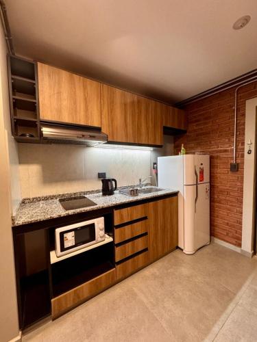 a kitchen with wooden cabinets and a white refrigerator at DPTO 204 Edif Loftier in Posadas