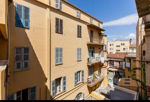 un grand bâtiment jaune avec des fenêtres à volets bleus dans l'établissement joli studio centre ville, à Ajaccio