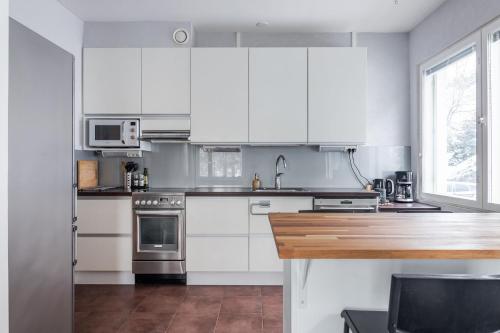 a kitchen with white cabinets and a wooden counter top at Beautiful 1BR Apartment near Lahti Center with Free Parking in Lahti