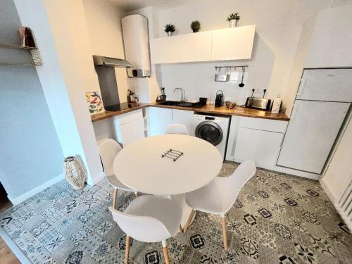 une cuisine blanche avec une table et des chaises blanches dans l'établissement Toulouse grand T2 climatisé Proche Place Dupuy, à Toulouse