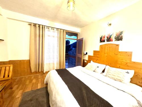 a bedroom with a large bed and a window at Bayith Cafe and Stay in Manāli