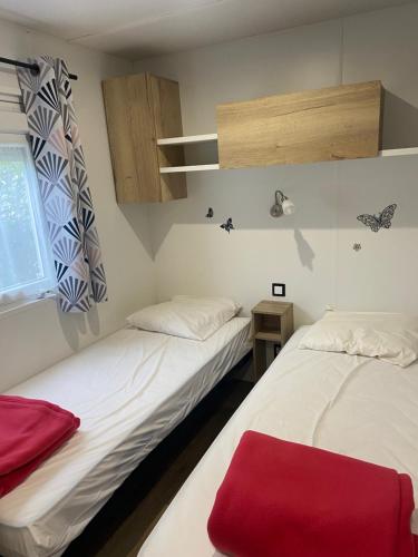 - 2 lits dans une petite chambre avec une couverture rouge dans l'établissement Joli Mobil-home spacieux Mar Estang, à Canet