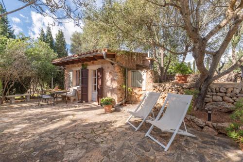 a patio with two white chairs and a house at Can Pina - Eco Groc - in Costitx