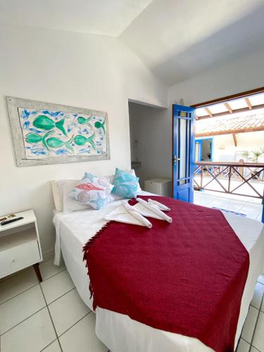 a bedroom with a bed with a red blanket at Vila Mucugê Pousada e Hostel in Arraial d'Ajuda