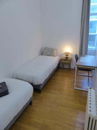 une chambre avec deux lits, un bureau et une fenêtre dans l'établissement VIARME - Grand T4, 6 pers au calme en centre ville, à Nantes