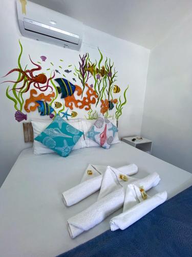 a white bed with towels and a painting on the wall at Vila Mucugê Pousada e Hostel in Arraial d'Ajuda