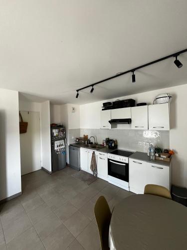 une cuisine avec des armoires blanches et une table à l'intérieur dans l'établissement Auberge Chambre La Bienveillance, à Lormont